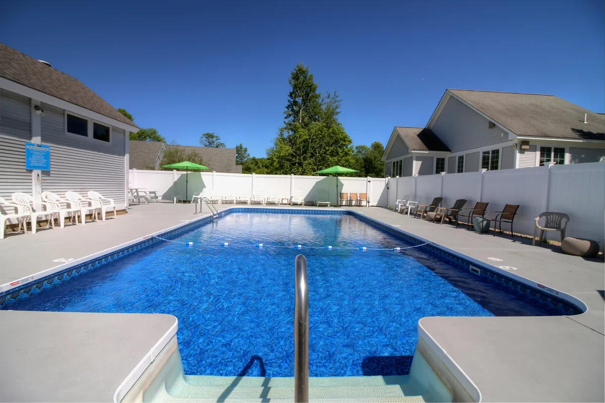 A close-up exterior shot of the swimming pool area, highlighting inviting lounge chairs and green umbrellas. The relaxed mood and well-appointed amenities make it easy to picture unwinding poolside after a day of adventure.