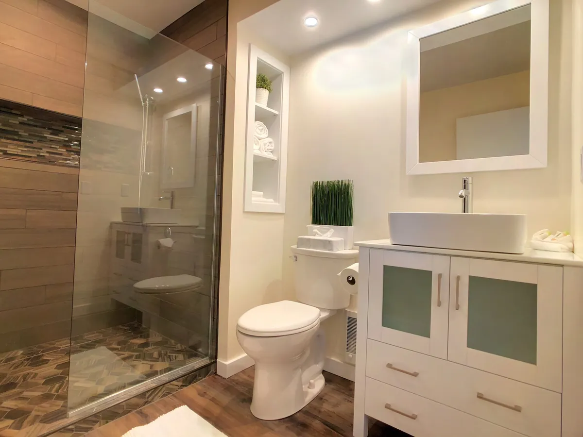 A modern bathroom scene showing a glass shower enclosure, a stylish sink, and decorative plants. The space feels tranquil and refreshing, with an emphasis on clean design and moments of solitude.