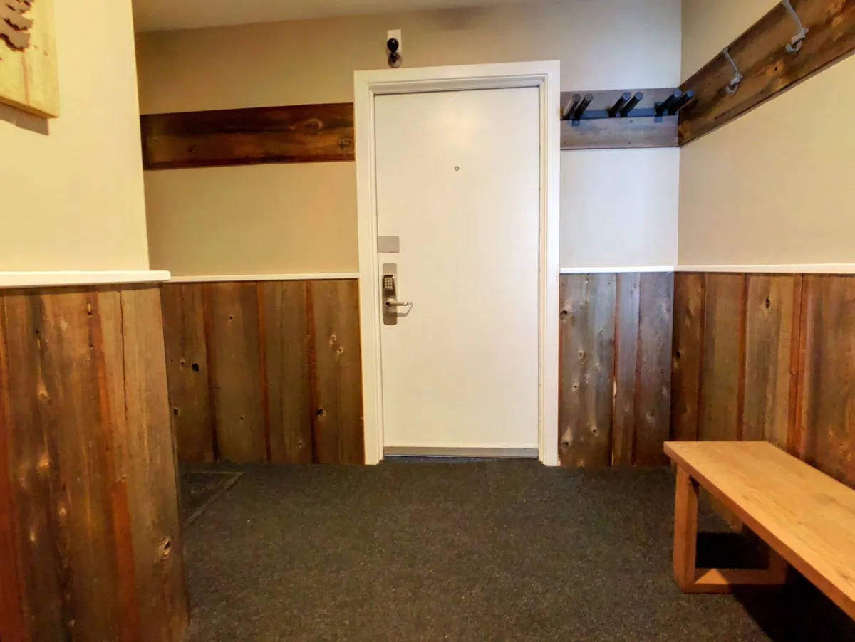 A welcoming front entrance featuring a wooden bench and coat hooks, creating a cozy and inviting first impression. The scene captures the transitional space where guests arrive, set down belongings, and prepare for their eventful stay.