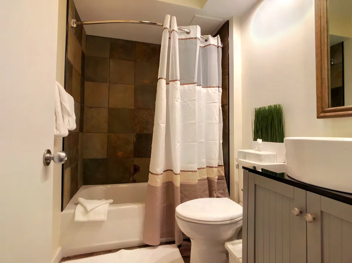 A modern ensuite bathroom with a bathtub and shower combo, a sleek vanity, and a well-lit mirror. The space is clean, calm, and perfect for unwinding after a day outdoors, aligning with the description of the ensuite bathroom in the narrative.