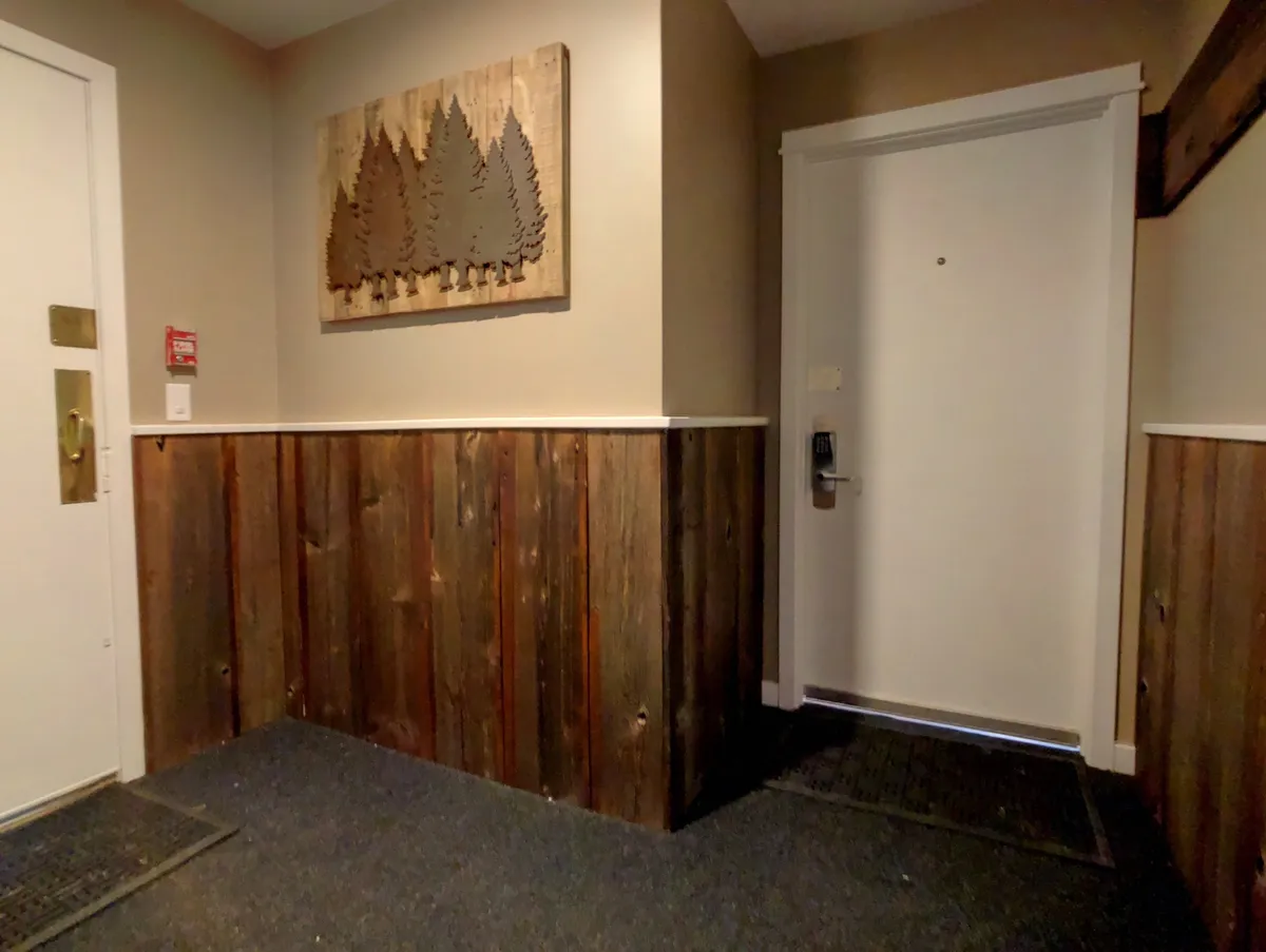 The stylish main entrance of the condo, featuring wooden wall art and textured paneling. This cozy entryway sets an inviting tone, suggesting a welcoming return after an evening out.
